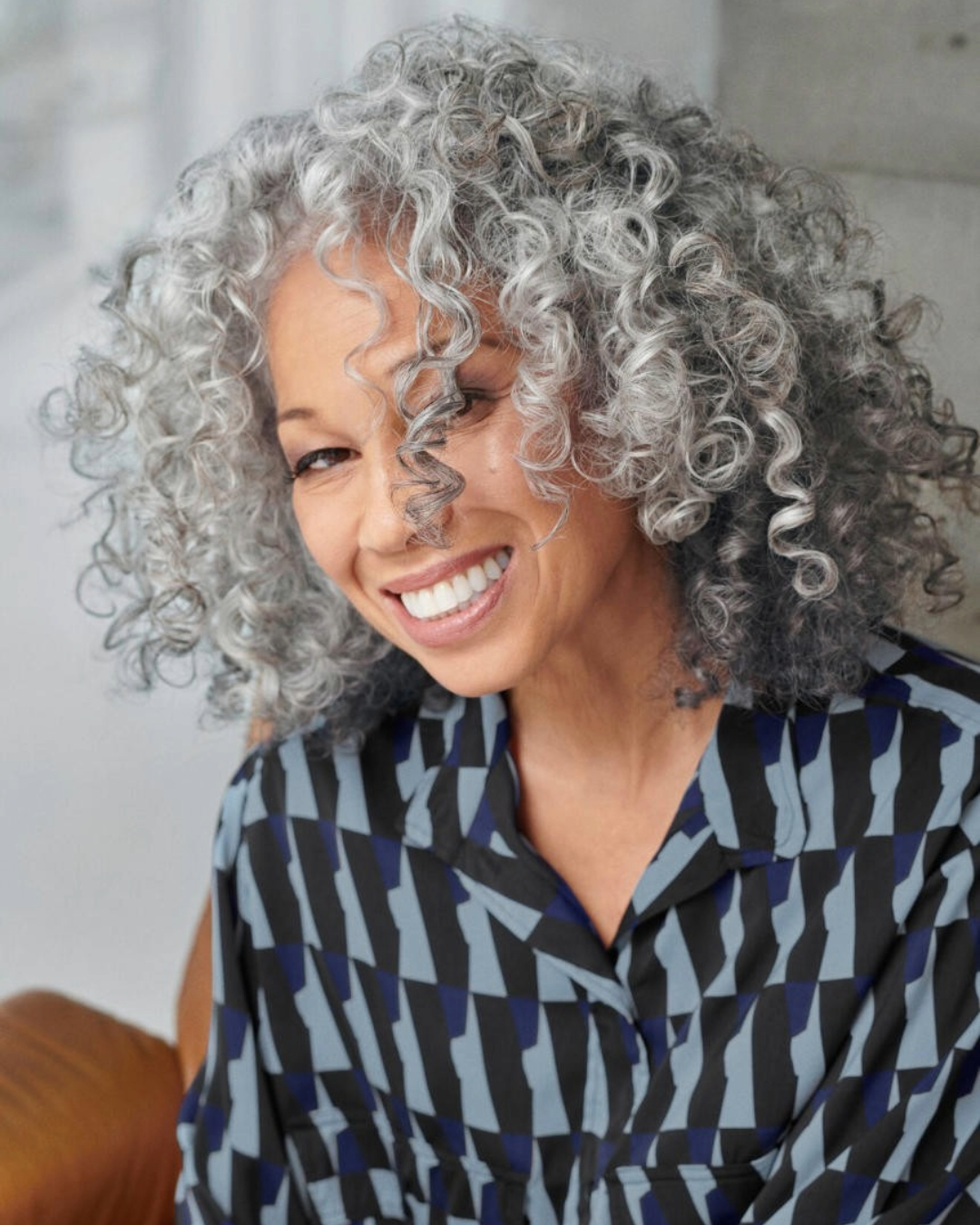 curly mid length hair cut with salt and pepper hair colour